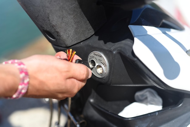 Hand turning the key of ignition of motorbike