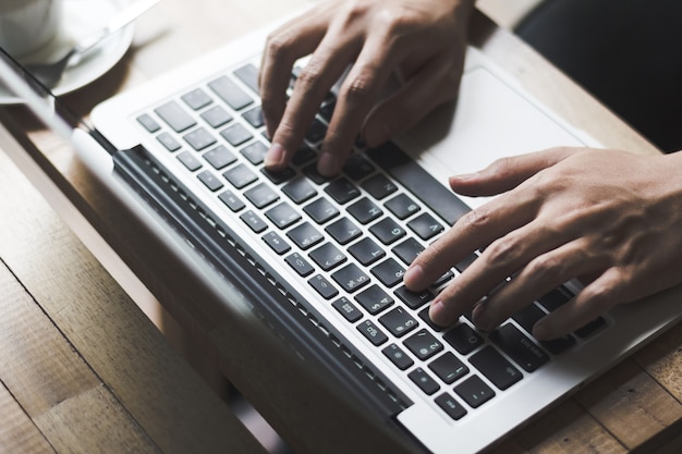 hand typing keyboard on wooden table at coffee shop