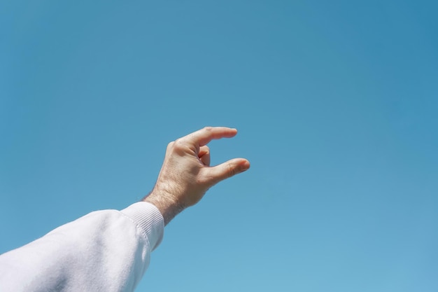 hand up in the air gesturing in the blue sky, blue background