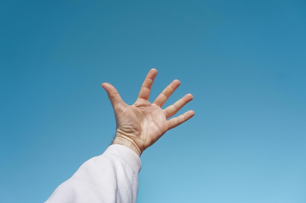 hand up in the air gesturing in the blue sky, blue background