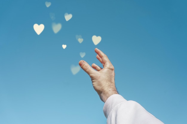 hand up in the sky touching a heart shape, love emotions in valentine's day