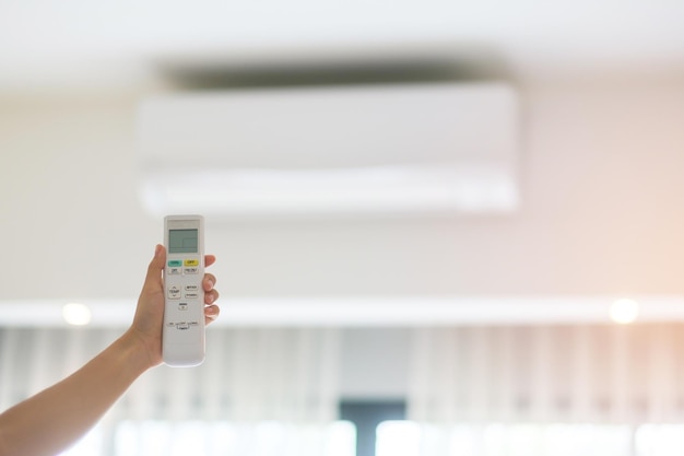 Hand using remote controller for adjust Air conditioner inside the room of office or home