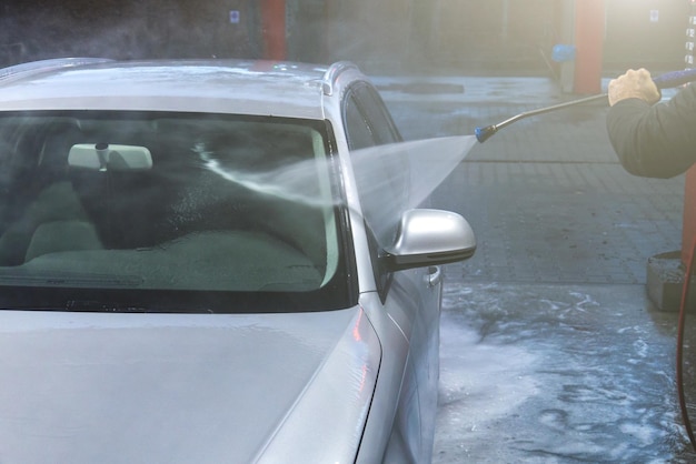 Hand washing with high pressure water spraying water on the car Selfservice car wash