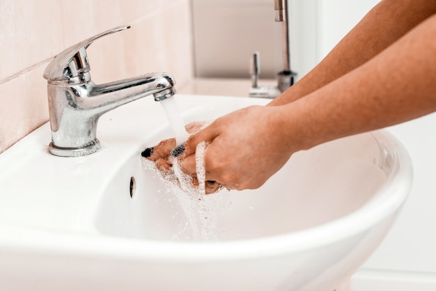 Hand washing with soap in a sink in a public place. Hygiene concept. Washing hands with soap under the faucet with water