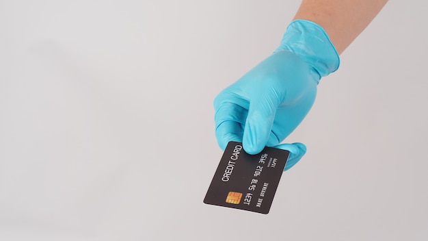 Hand wear blue medical glove holding Black credit card on white background.