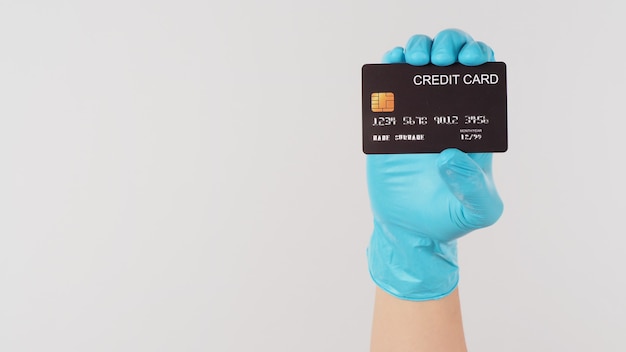 Hand wear blue medical glove holding Black credit card on white background.