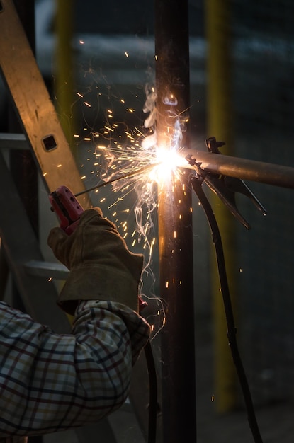 Hand welder in protective glove Welding process closeup