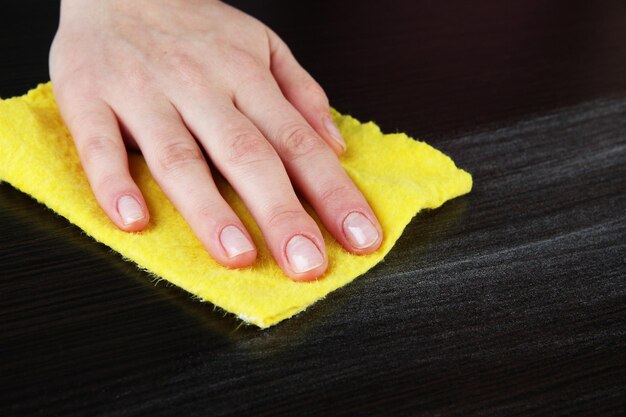 Photo hand wiping wooden surface with yellow rag