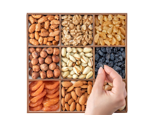 Hand with assorted nuts and dried fruit collection Different superfoods Vegetarian snack of different nuts organic mixed nuts background