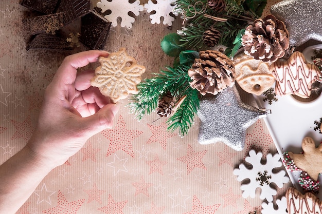 Hand with Christmas biscuit, eating biscuits, Christmas decoration, on a background of stars. Christmas dinner, sharing with the family