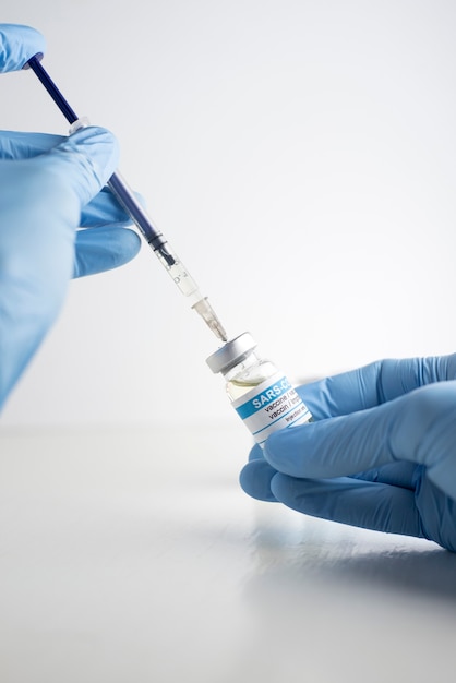 hand with coronavirus vaccine and syringe defocused white background