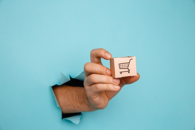 Hand with a delivery box through a blue paper hole