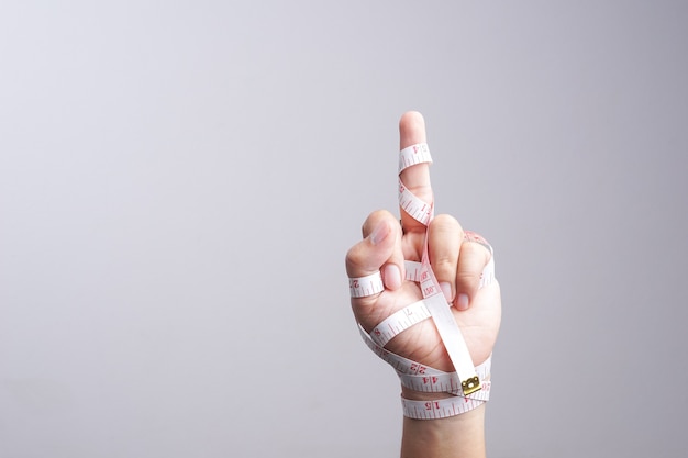 Hand with fuck you gesture wrapped by measuring tape