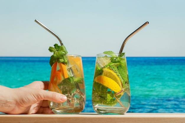 Hand with gin tonic cocktail on summer beach