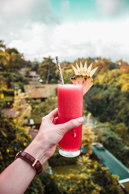 Hand with glass of watermelon juice on the jungle tropical background on Bali island, Indonesia