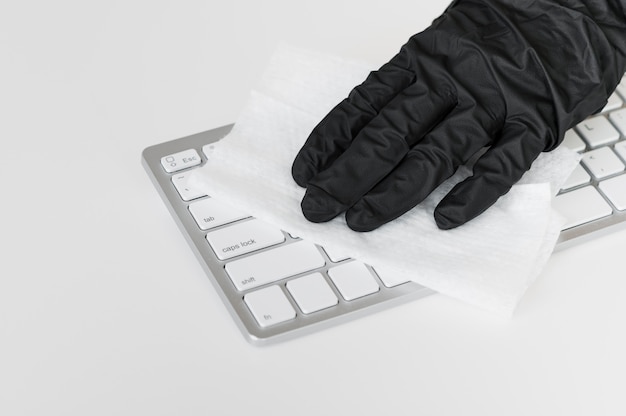 Hand with glove disinfecting keyboard surface