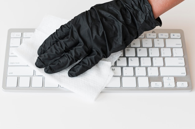 Photo hand with glove disinfecting keyboard