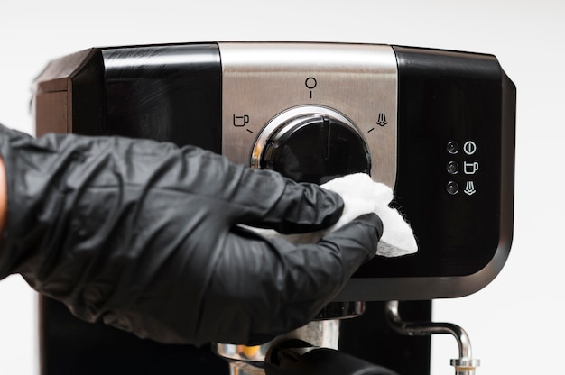 Hand with gloves disinfecting instant coffee machine