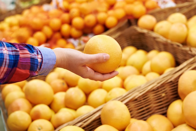 Hand with grapefruit in fruit department in the supermarket