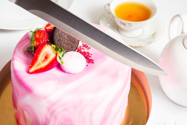 Hand with a knife to cut the cake on party birthday cake delicious biscuit pink fondant cake