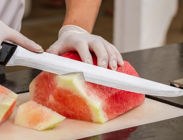 Hand with a knife cuts a watermelon