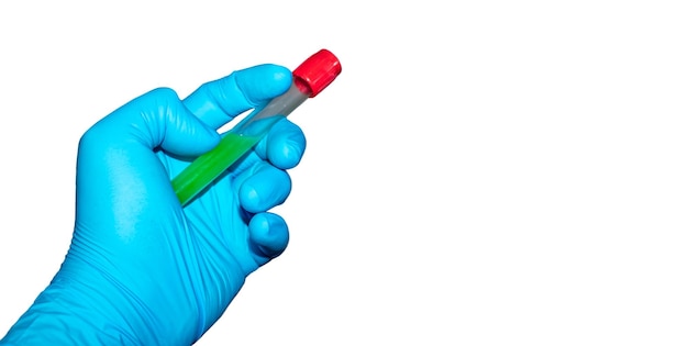 Hand with latex surgical glove holds sealed test tube with green liquid on white background.