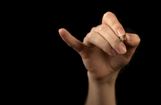 Hand with pen isolated on a black background. Concept of marking checklist, business work job drawing, mark pointing photo