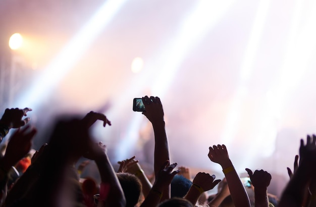 Hand with phone records live music festival People taking photograph with smart phone during concert