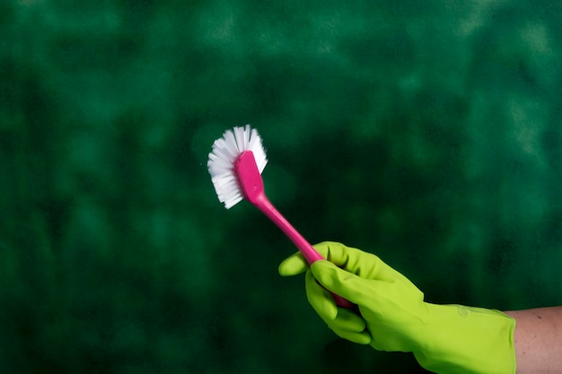 Hand with protective glove holding packaging of cleaning products used for home hygiene