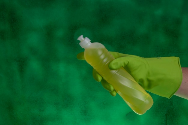 Hand with protective glove holding packaging of cleaning products used for home hygiene