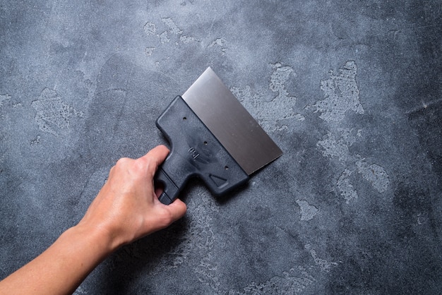 Hand with  putty knifes on grey background