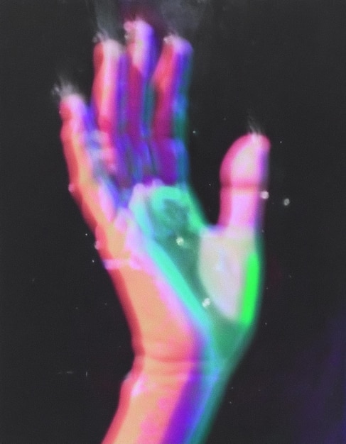 a hand with a rainbow colored hand in the dark