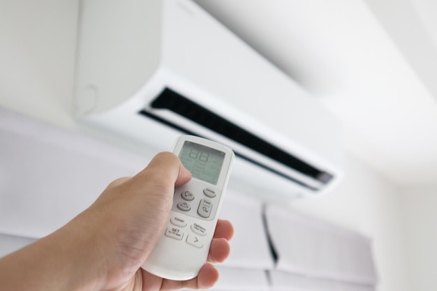 Hand with remote control directed on air conditioner