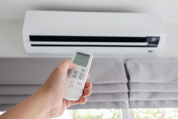 Hand with remote control directed on air conditioner