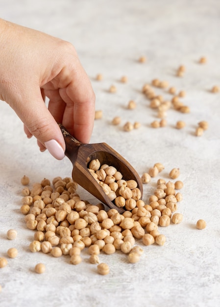 Hand with a scoop of raw dry chickpea  close up