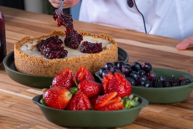 hand with spoon spreading berry jam on sweet pie