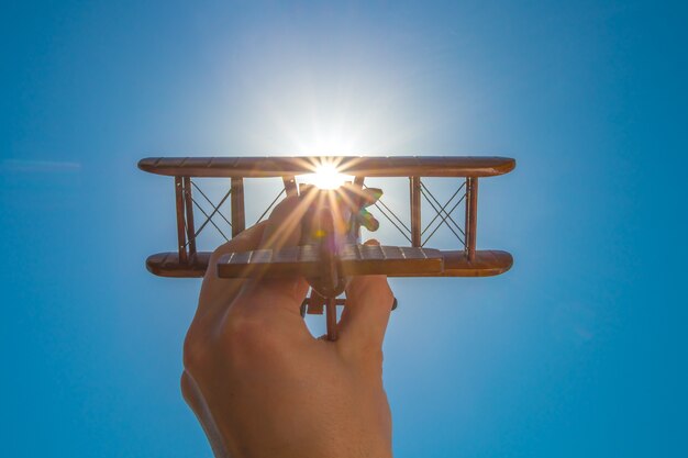 The hand with a toy plane on the background of the clear sky