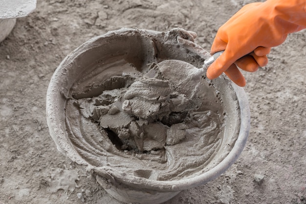 hand with trowel and bucket with mortar at consturction site