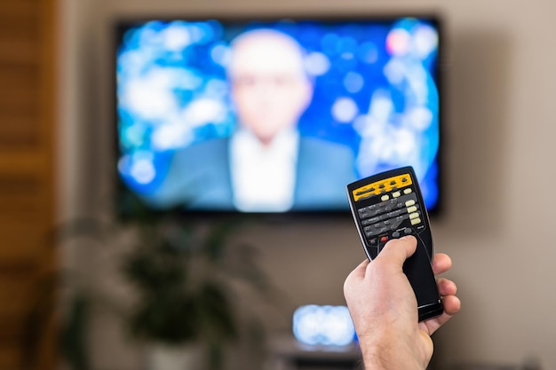 A hand with a TV remote control. The concept of remote communication. Play button icons. Control of the TV's media player.