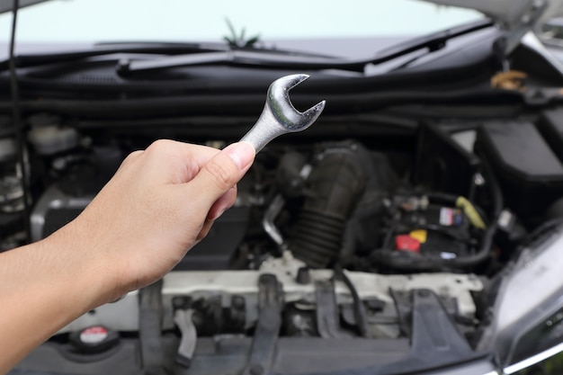 hand with wrench on car engine