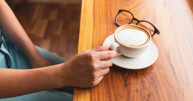 Hand of  woman holding a cup of coffee relaxed in a cafe