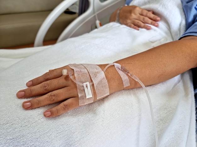 The hand of woman patients with a stick tube of saline solution in a hospital room