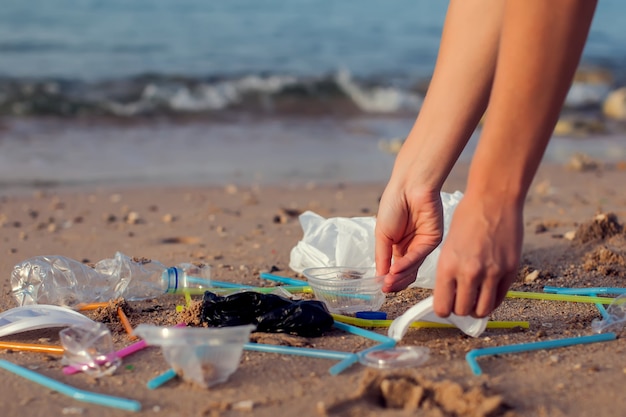 Hand woman picking up plastic bottle cleaning on the beach , volunteer concept