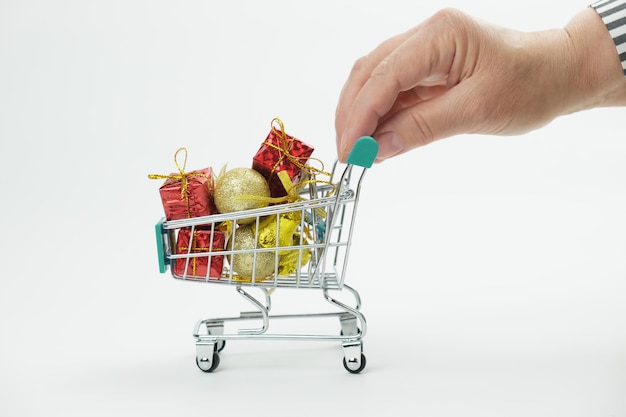 Hand woman rolls full of Christmas gifts and Christmas decorations little shopping cart