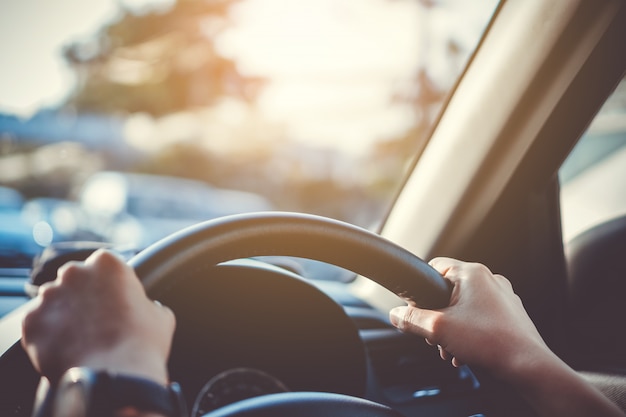 Hand of a woman on steering wheel driving a car