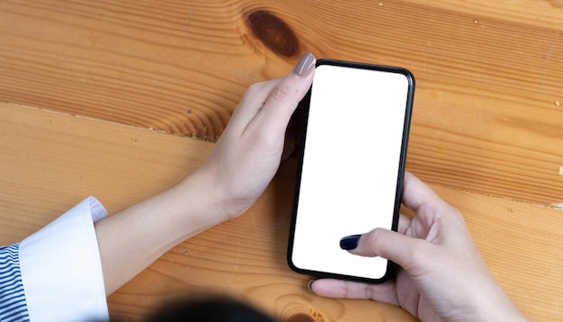 Hand woman using a telephone empty screen smart phone and computer on wooden table top view