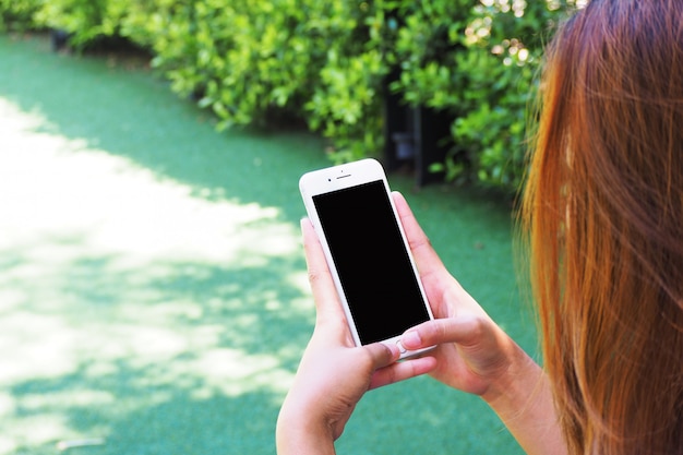 Hand woman using a telephone, empty screen smart phone in garden