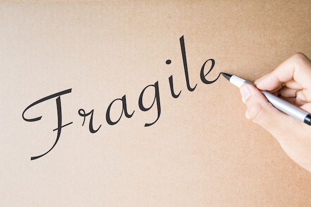 Hand writing fragile on brown paper background