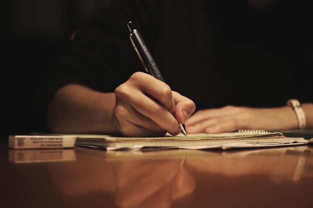 A hand writing on a notebook with a pen