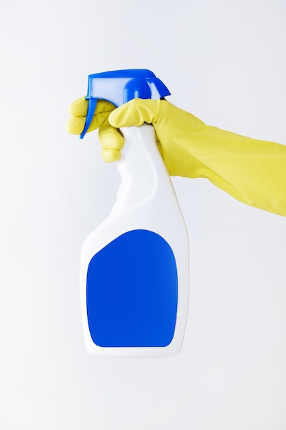 Hand in yellow glove holds spray bottle of liquid detergent on white background